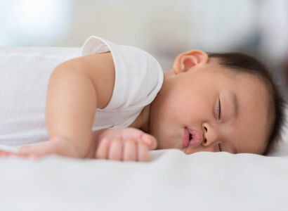 happy,asian,newborn,baby,lying,sleeps,on,a,white,bed